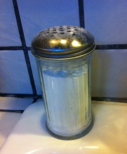 Baking soda in a parmesan cheese container on the sink. 